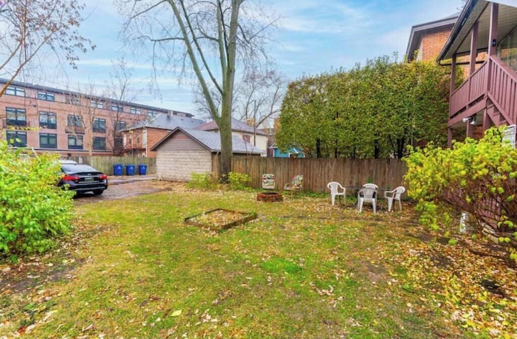 Une cour arrière avec une clôture en bois, un petit abri de jardin et une voiture garée dans la rue.