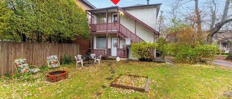 A two-story house with a balcony, a fenced yard, and a small garden area.