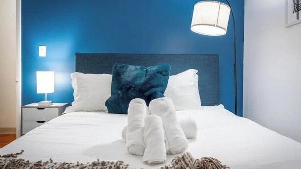 A neatly made bed with white linens, a blue headboard, and a single white bedside lamp. - OSU - Heart of Short North -STEPS from High ST-OSU (Columbus)