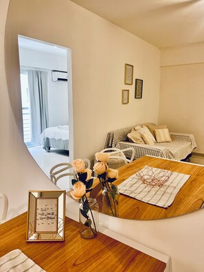 Een hotelkamer met een bed, een slaapbank, een eettafel met een bloevas en een lijst aan de muur.