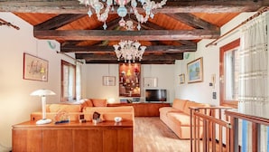 Una sala de estar acogedora con muebles de madera, una araña y un televisor.
