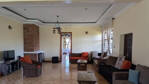 A spacious living room with a brick accent wall, a television, and a fireplace. - Luxury 9 Rooms Fullhouse in Karen Nairobi (Nairobi)