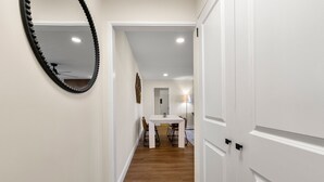 A hallway with a wooden floor, white walls, and a dining area with a table and chairs. - Stylish 1-bedroom condo Downtown Atlanta (Atlanta)