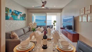 A dining area with a table set for two, a television, and a scenic view through the window. - Entire condo in Puerto Vallarta, Mexico (Puerto Vallarta)