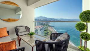 A balcony with wicker furniture, a glass table, and a view of the ocean and cityscape. - Entire condo in Puerto Vallarta, Mexico (Puerto Vallarta)