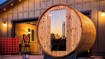 Une structure en forme de tonneau, faite de bois, se trouve devant un bâtiment doté d’une porte de garage.