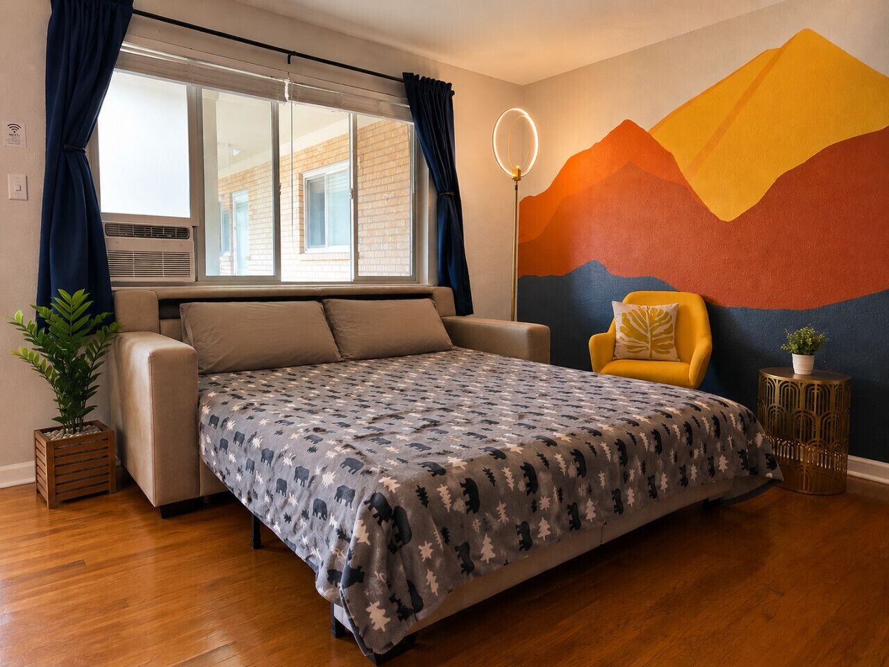 Een slaapkamer met een bed, een stoel, een raam, een wanddecoratie en een plant.