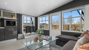 Un salon moderne avec une table basse en verre, un canapé gris et un téléviseur.