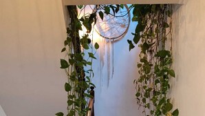 A staircase with wooden steps and a handrail, surrounded by climbing plants and a dreamcatcher hanging from the ceiling. - Ben House - House with 3 bedrooms (Unknown)