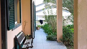 A covered outdoor area with a tiled floor, a bench, and potted plants. - Ben House - House with 3 bedrooms (Unknown)