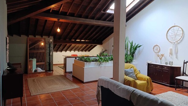 A spacious living area with a high ceiling, a central island with plants, a yellow sofa, and a cabinet. - Ben House - House with 3 bedrooms (Unknown)