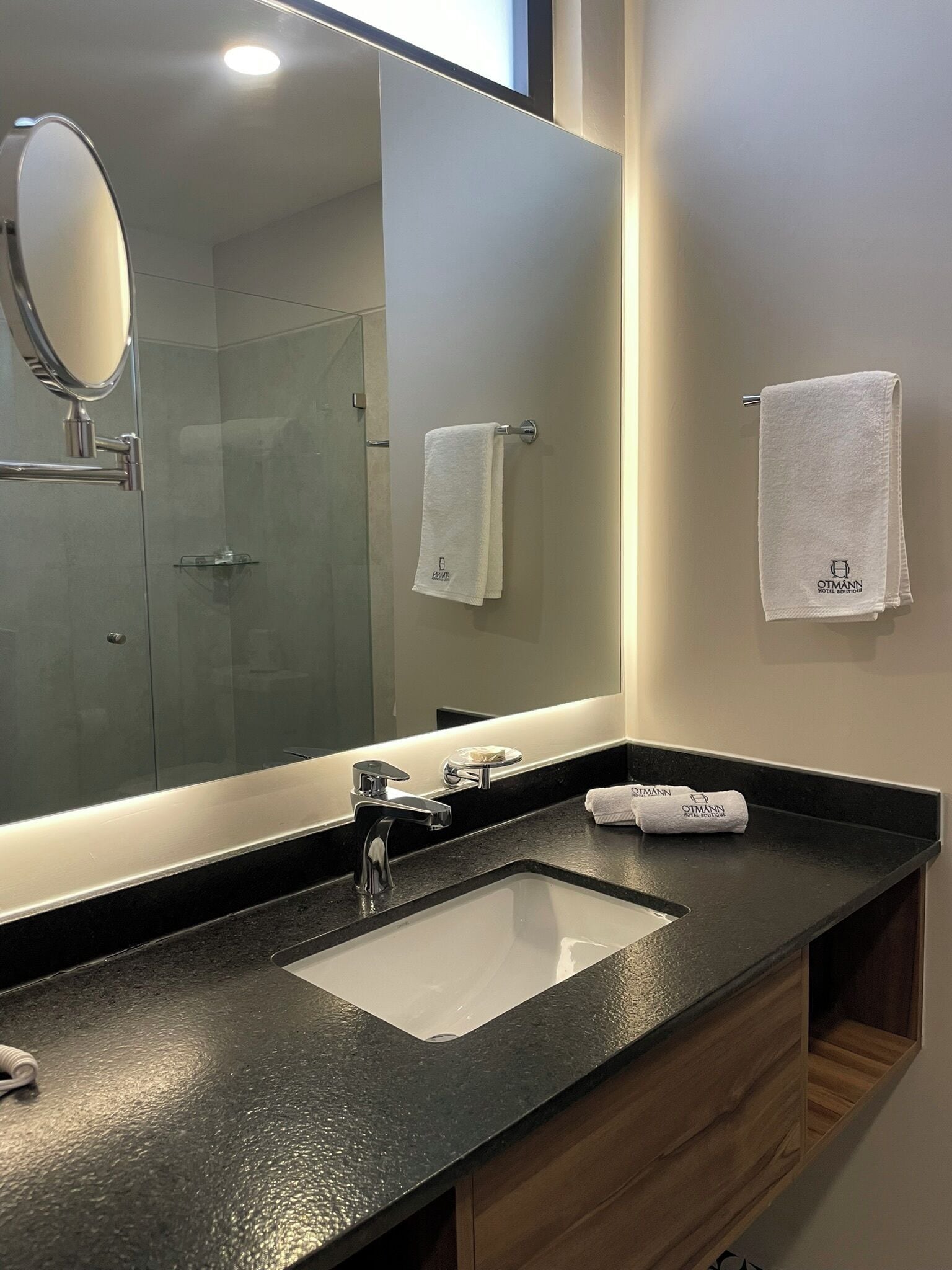 A modern bathroom with a large mirror, a sink, and a towel rack.