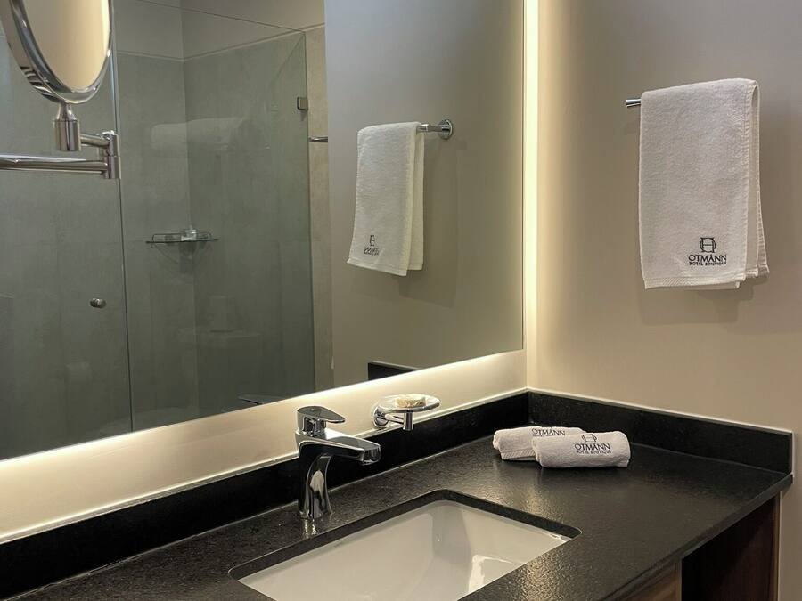 A modern bathroom with a large mirror, a sink, and a towel rack.
