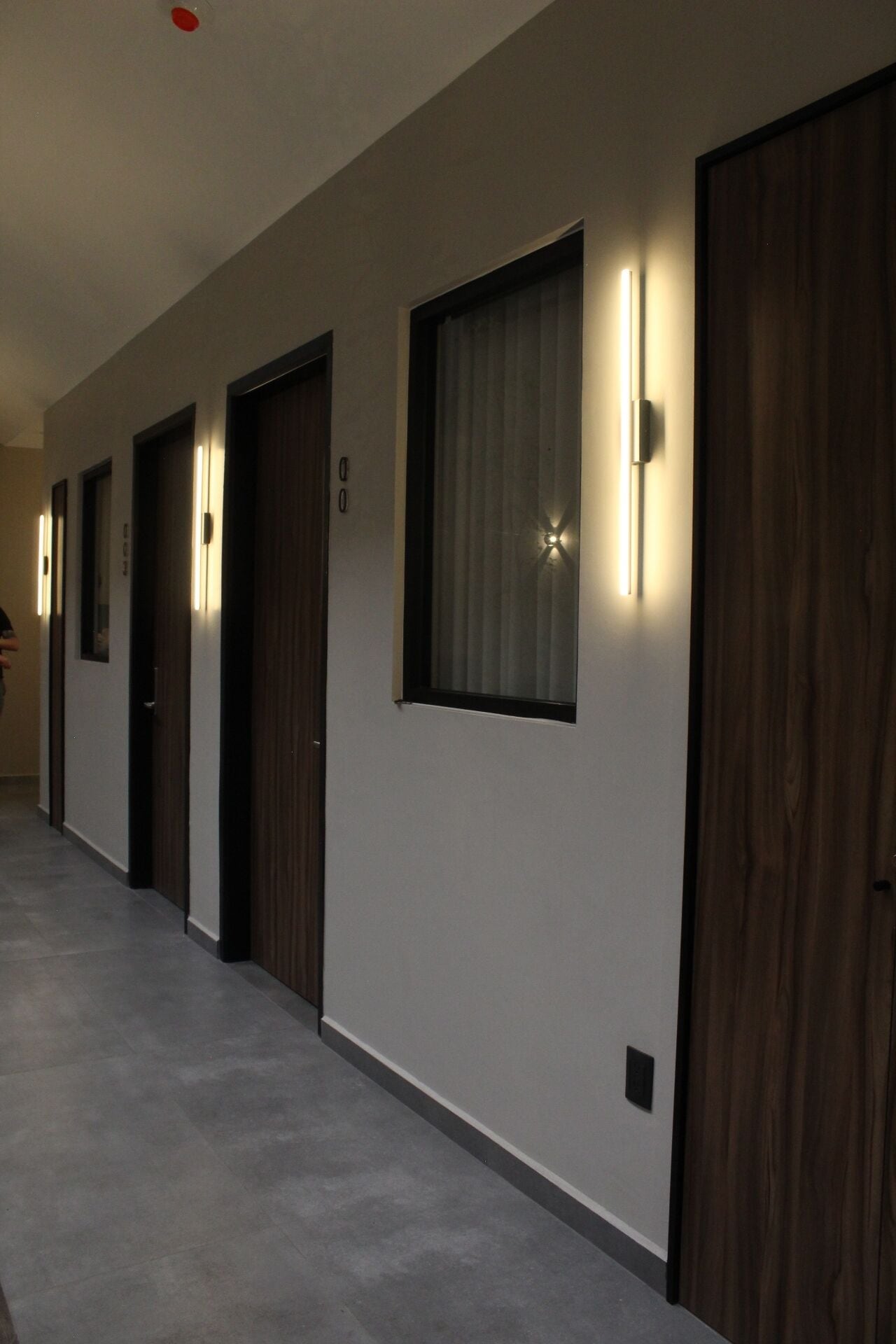A hallway with multiple doors, each with a light above.