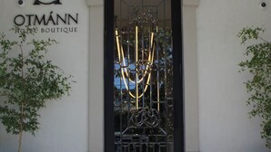La entrada al HOTEL OTMANN BOUTIQUE, con un portón negro y un diseño metálico geométrico.