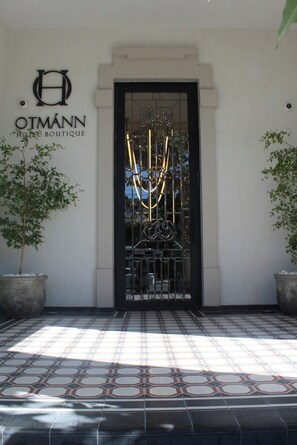 De ingang van OTMANN HOTEL BOUTIQUE met een zwart hek en een geometrisch metalen ontwerp.