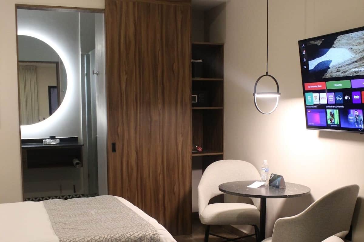 Een hotelkamer met twee bedden, een bureau met stoel, een televisie en een garderobe.