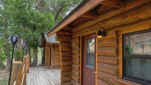 Una cabaña de troncos con una terraza de madera, una puerta principal y una ventana.