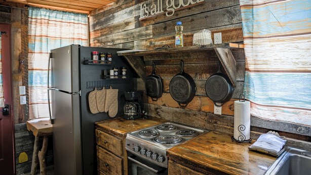 Una cocina rústica con paredes de madera, una estufa de acero inoxidable y un refrigerador.