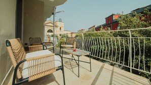 A balcony with wicker furniture, a table, and a view of buildings and greenery.