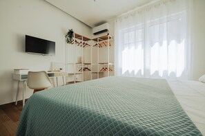 Une chambre d’hôtel comprenant un lit, un bureau, une chaise, une télévision et une armoire.