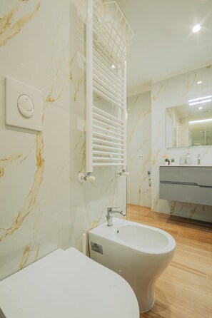 Une salle de bain moderne équipée d’un bidet, d’un porte-serviettes et d’une coiffeuse avec un miroir.