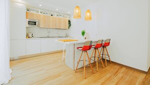 A modern kitchen with white cabinets, a wooden countertop, and two pendant lights.