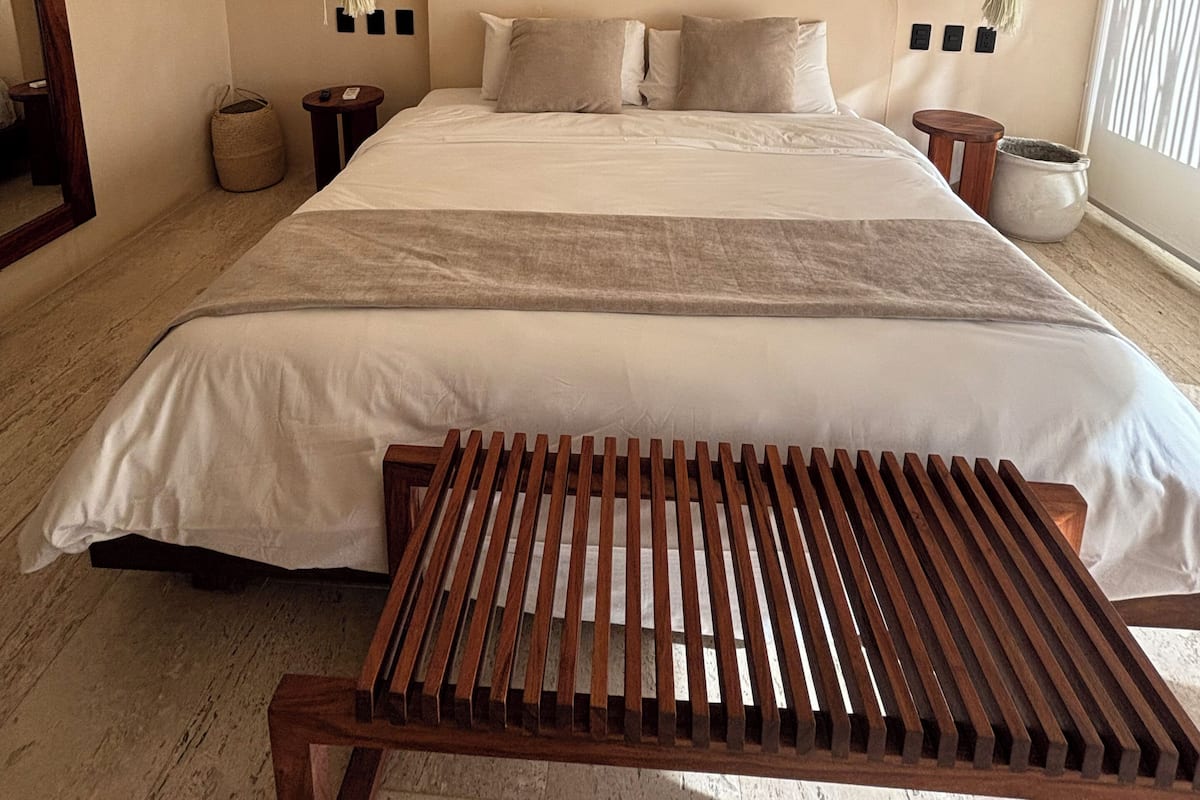 A bedroom with a bed, bedside tables, a hanging light fixture, and a window.