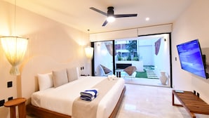 A modern hotel room with a large bed, a ceiling fan, a TV, and a view of the outdoor area. - Loch Tulum by The Spot Rentals (Tulum)