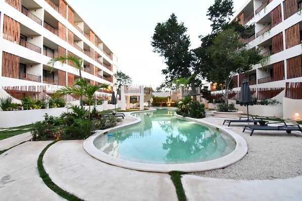 Ein Poolbereich mit kreisförmigem Design, umgeben von einem weißen Gebäude mit hölzernen Balkonen.