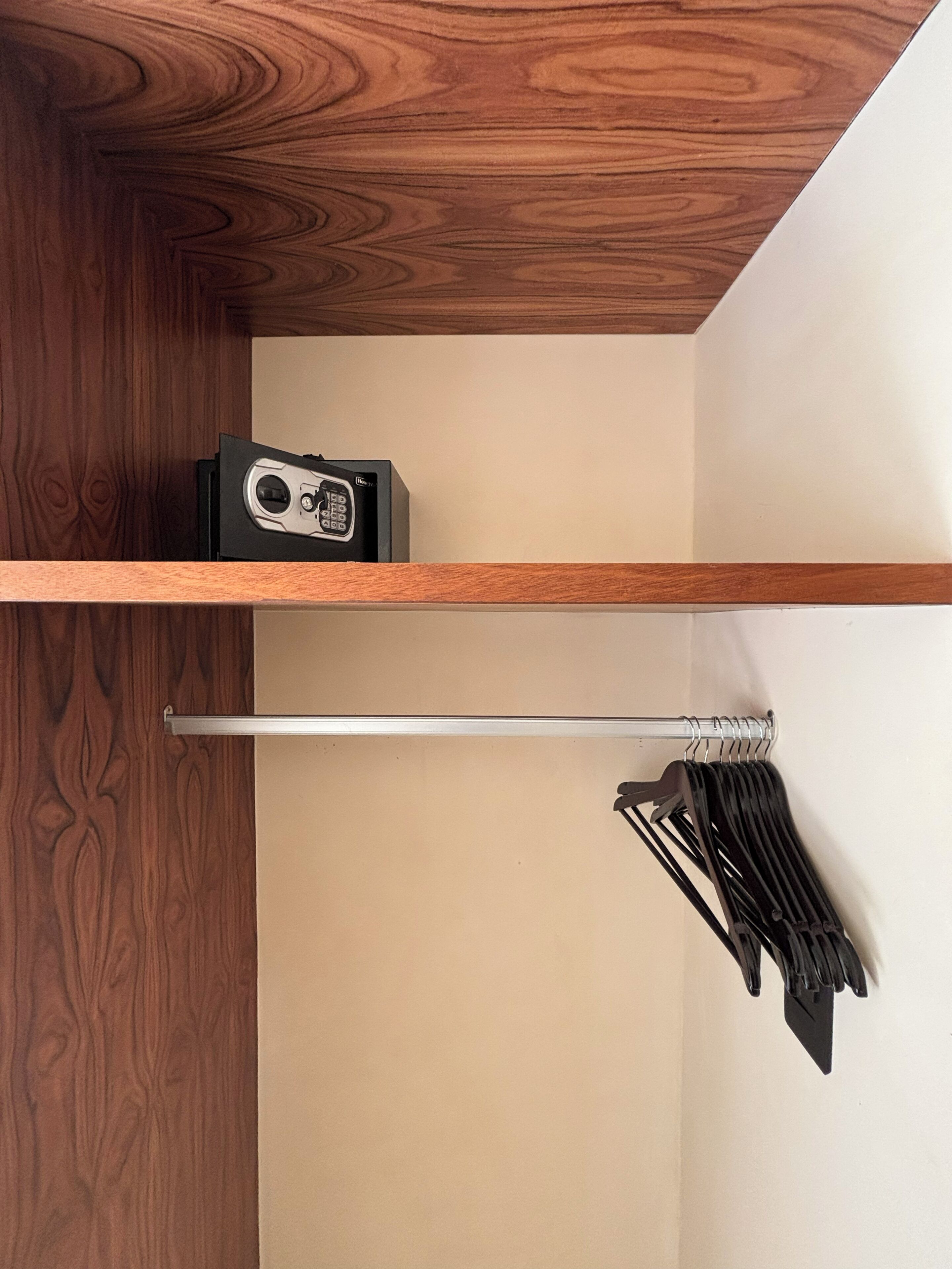 Un plafond en bois, une étagère sur laquelle se trouve un objet noir, et un présentoir en métal contenant des objets noirs.