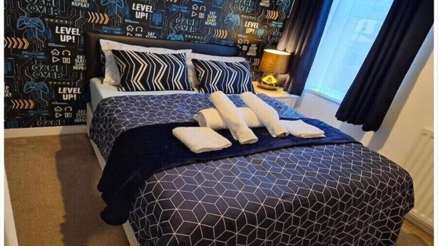 A hotel room with a bed, patterned wallpaper, and a window with curtains. - Fantastic Large Room with  free parking (Chatham)