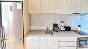 Eine Küche mit einem Edelstahl-Kühlschrank, einer Spüle, einer Kaffeemaschine, einem Toaster und einer Mikrowelle.