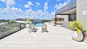 Eine Dachterrasse mit Pool, Liegestühlen und Topfpflanzen.