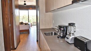 Eine moderne Küche mit einer Edelstahl-Arbeitsplatte, einer Kaffeemaschine, einem Mixer und einem Toaster.