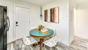 A dining area with a round table, white chairs, a potted plant, and artwork on the wall. - Walk to Casino: Home w/ Deck in Hot Springs! (Hot Springs)