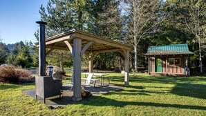 A covered outdoor area with a picnic table and a small building with a green roof. - Making Lasting Memories While Enjoying This Unique Glamping Experience! (Deming)