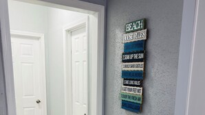 Un couloir doté d’un plancher en bois et d’un mur sur lequel est affiché un panneau indiquant les règles à respecter dans la maison de vacances.