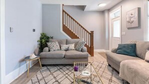 A living room with a grey sofa, a wooden staircase, and a patterned rug. - Luxury Chefs Kitchen - OSU/Short North - Sleeps 10 (Columbus)