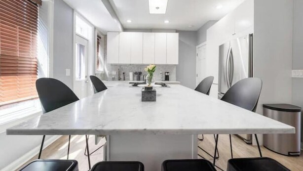 A modern kitchen with a central island, white cabinets, and black chairs. - Luxury Chefs Kitchen - OSU/Short North - Sleeps 10 (Columbus)
