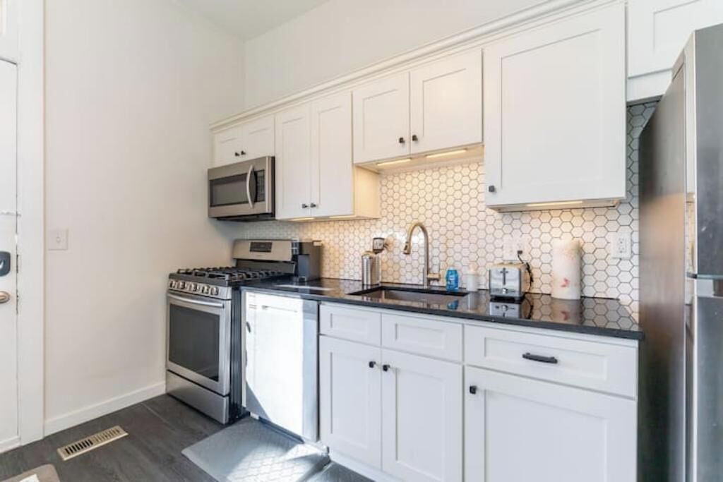 A kitchen with white cabinets, a stainless steel stove, a microwave, and a sink.