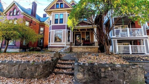A row of Victorian-style houses with a stone pathway leading to the front doors.