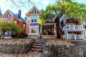 A row of Victorian-style houses with a stone pathway leading to the front doors.