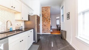 A modern kitchen with white cabinets, a black countertop, and a hexagonal tile backsplash.