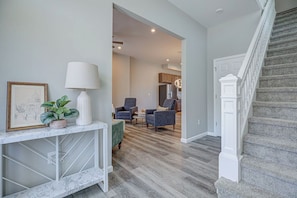 A modern interior with a marble console table, a framed picture, a potted plant, and a staircase. - Musketeer Manor ~ 5 bedrooms & 4.5 baths off street parking & central location!! (Cincinnati)