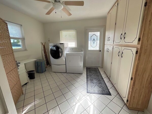 A laundry room with a ceiling fan, a washing machine, a dryer, and a small rug.