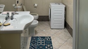 Une salle de bain moderne équipée d’un lavabo, de toilettes et d’un lave-linge.