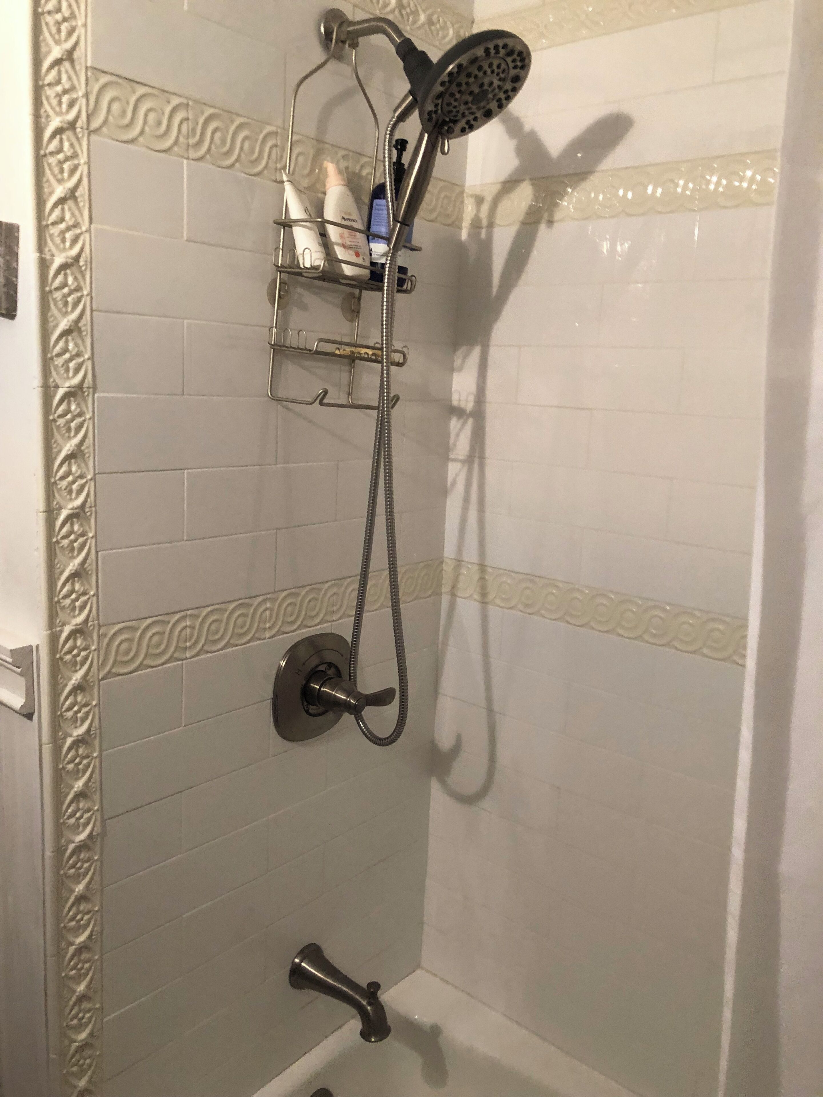 Un espace douche équipé d’un pommeau de douche à main, d’un robinet mural et d’un distributeur de savon.