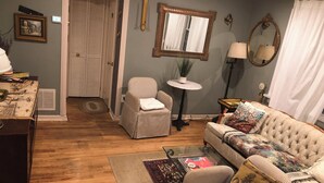 A living room with a striped armchair, a tufted sofa, a glass coffee table, and a patterned rug.