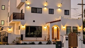 Un bâtiment à deux étages doté d’un balcon, de nombreuses fenêtres et d’un éclairage extérieur.